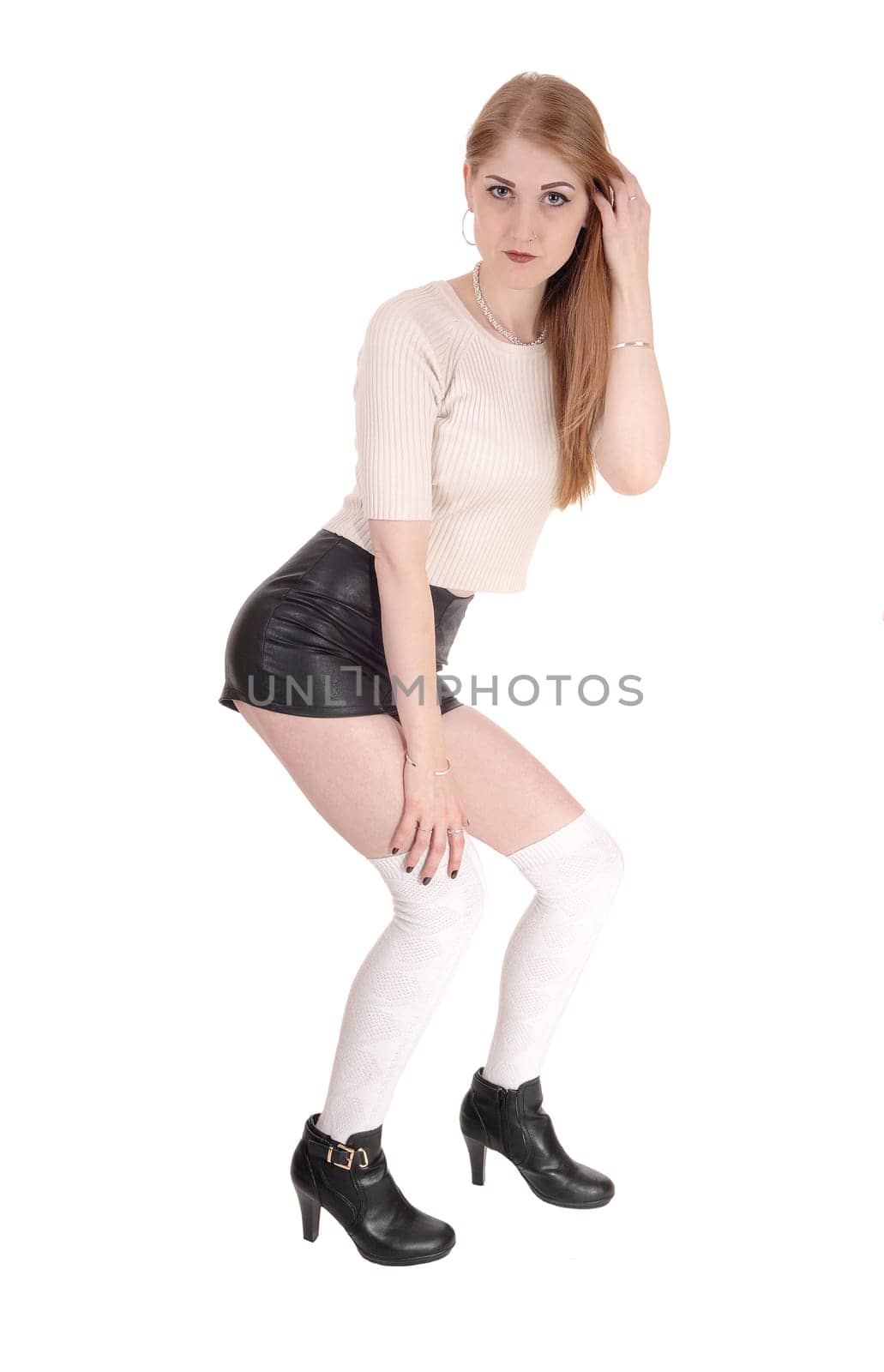 A young lovely brunette woman standing over white background in.black leather shorts and long white socks an high heels.