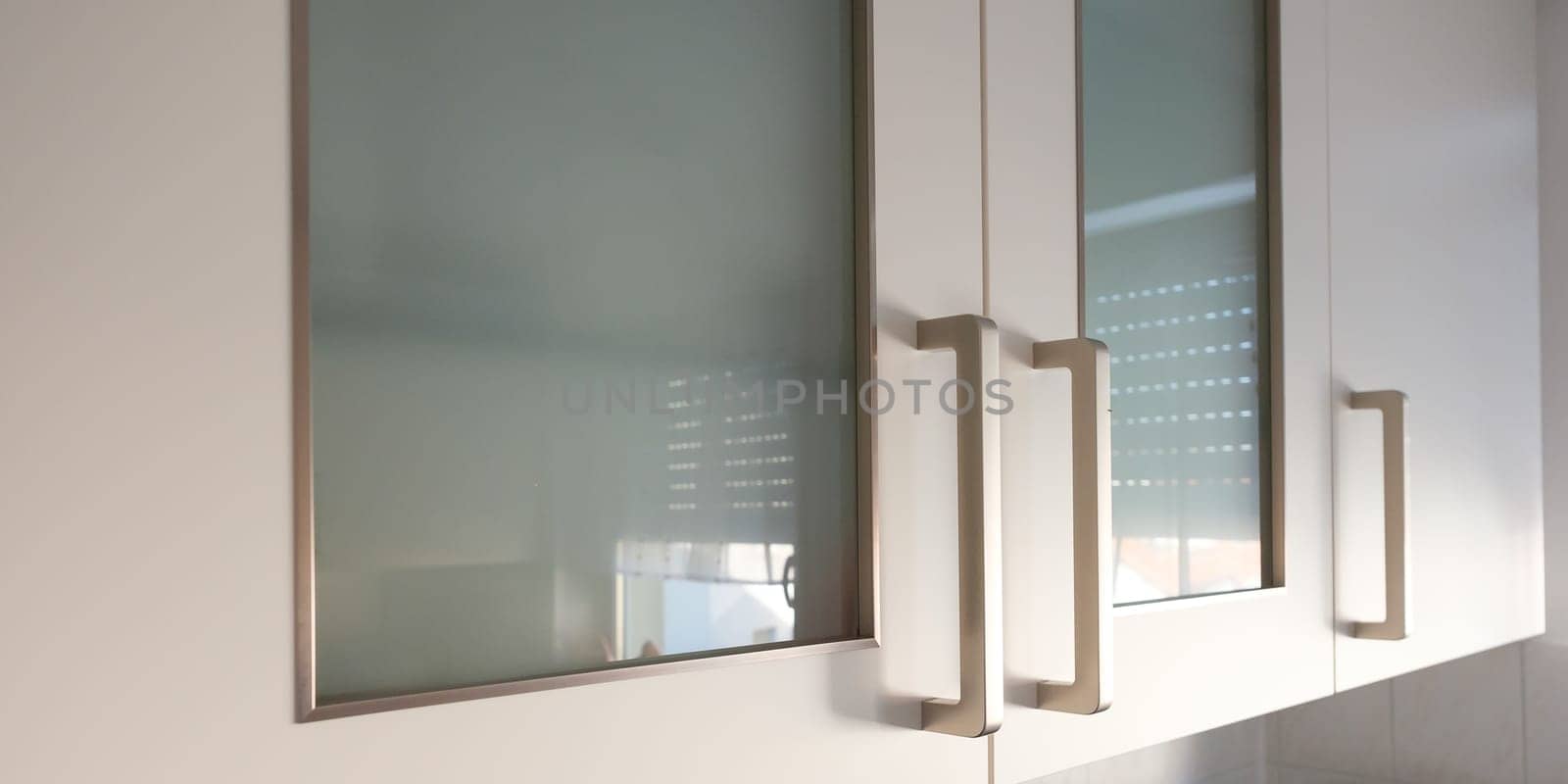 Hanging cabinet with glass and metal handle in kitchen