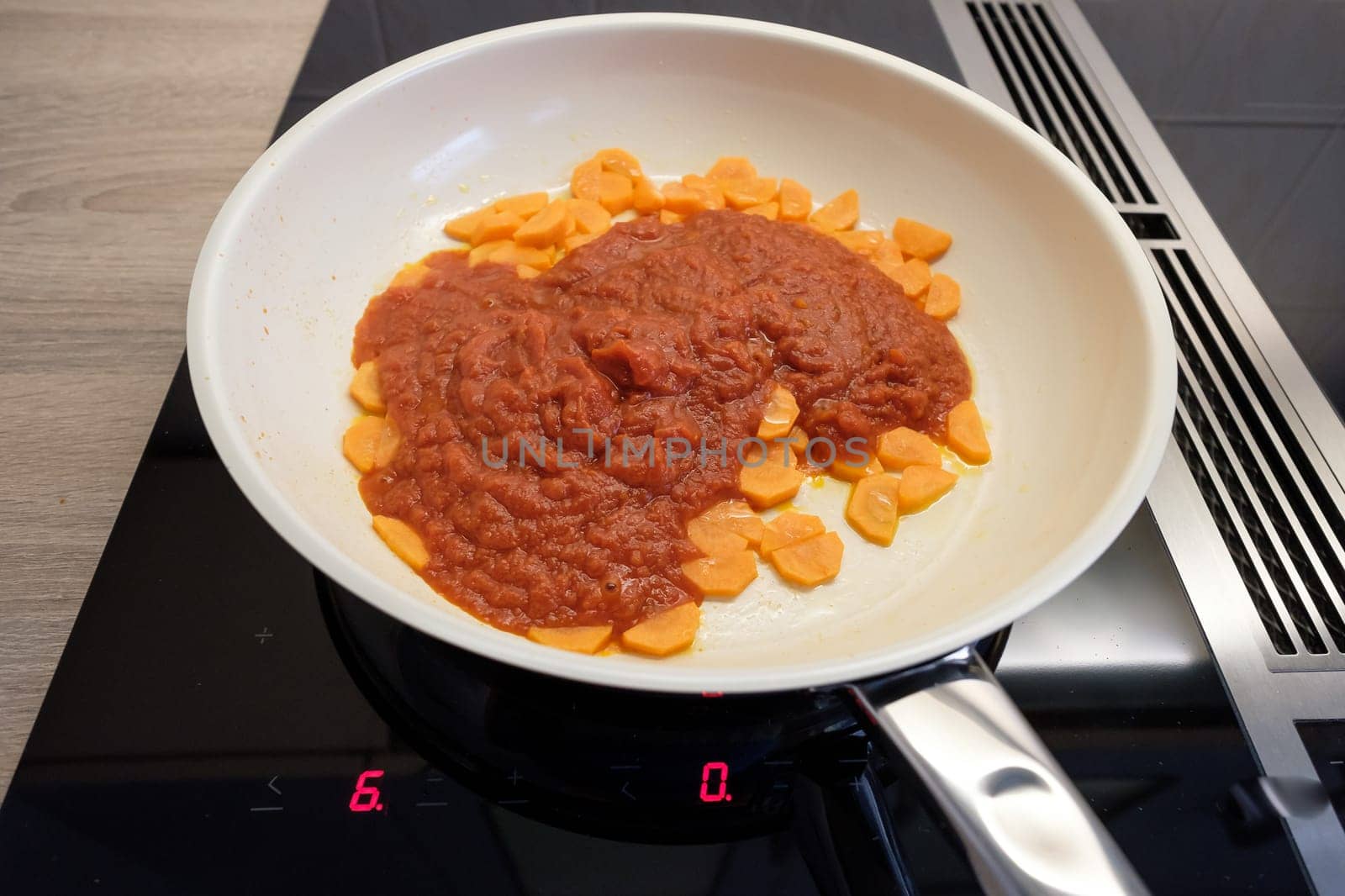 Carrots and tomato sauce in a pan on stove with induction