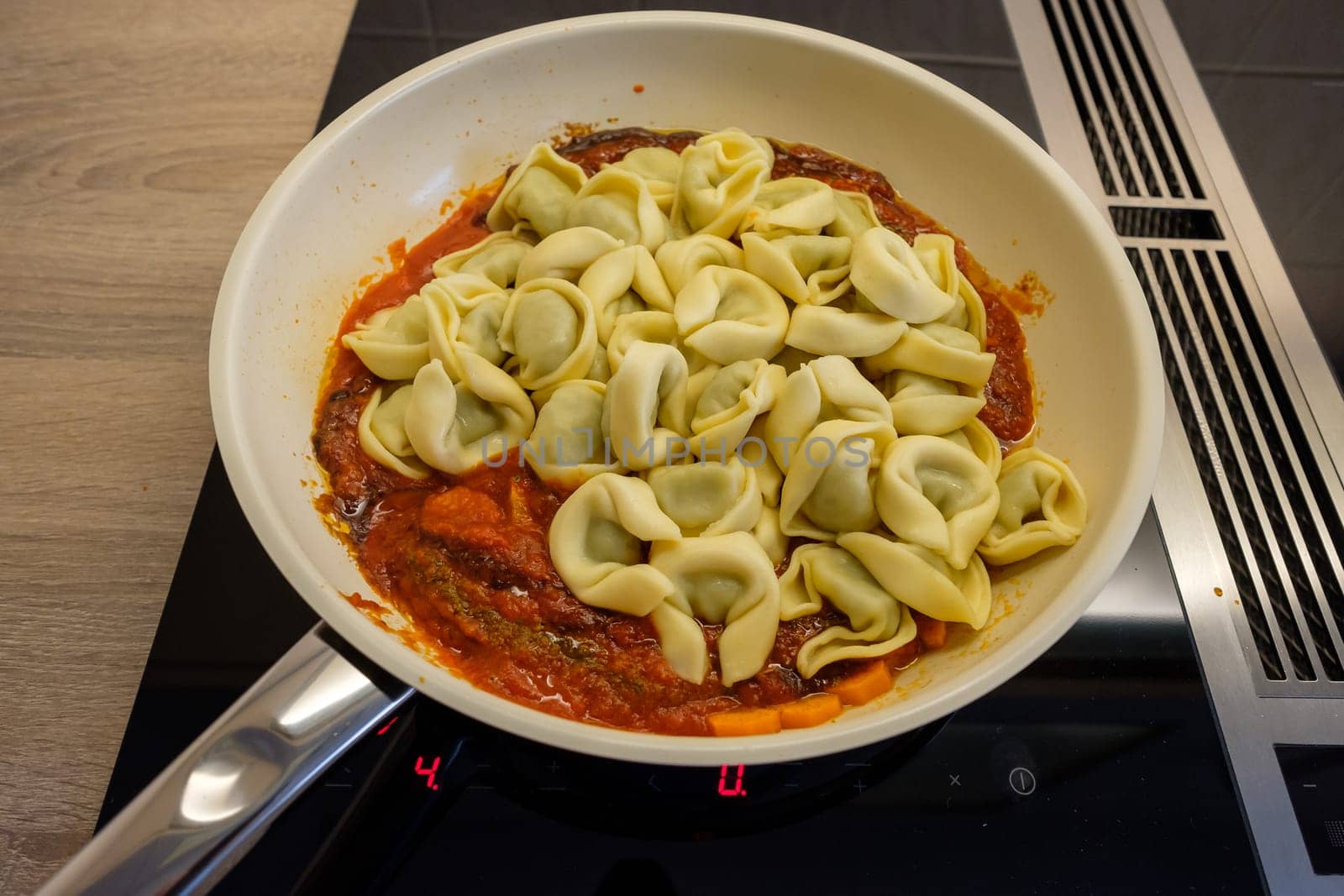 Pan with tortellini and tomato sauce on hob