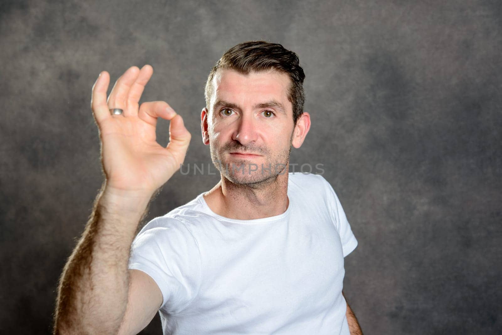 friendly young man show OK sign in front of gray background