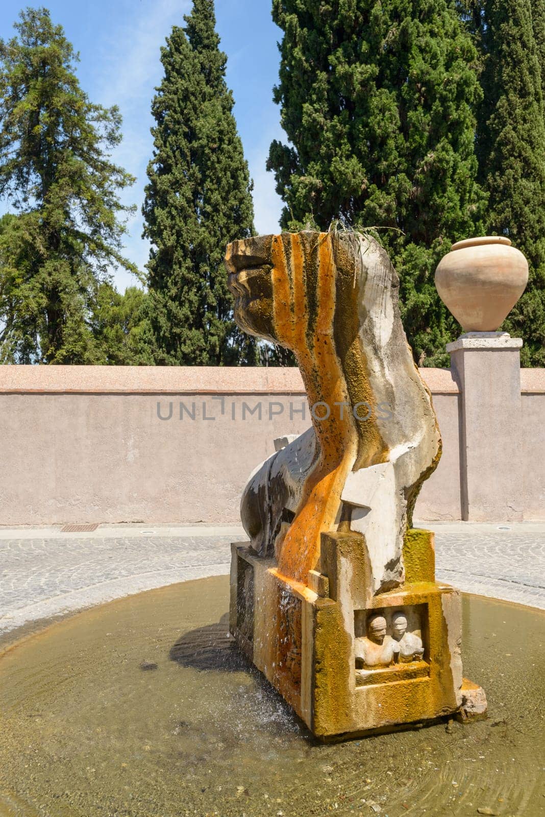 A fountain depicting a head, in a public square in Tivoli, Italy