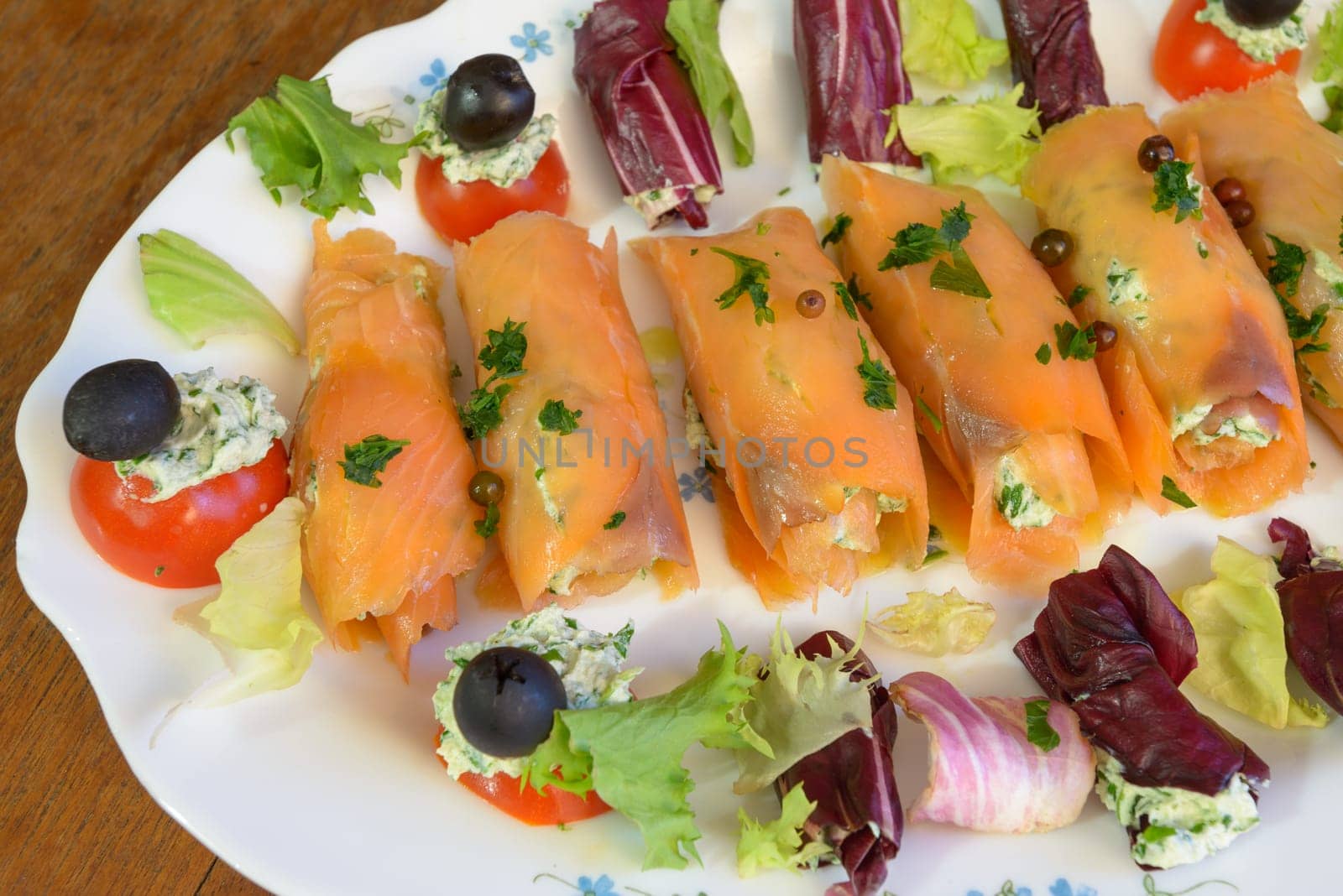 Wonderful and tasty smoked salmon rolls with salad tomatoes olive and cheese