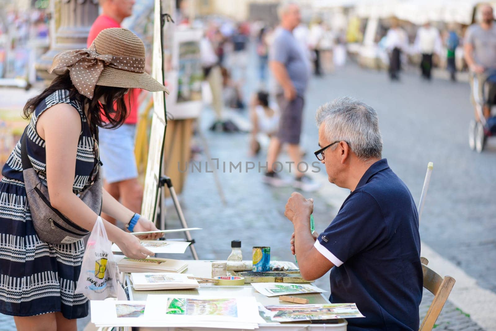Rome, Italy - August 22, 2015: the famous Navona square a man selling pictures to a tourist girl