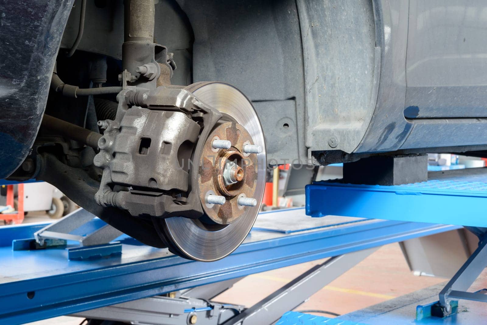 A car ready for fix on a workshop bridge, brakes are visible