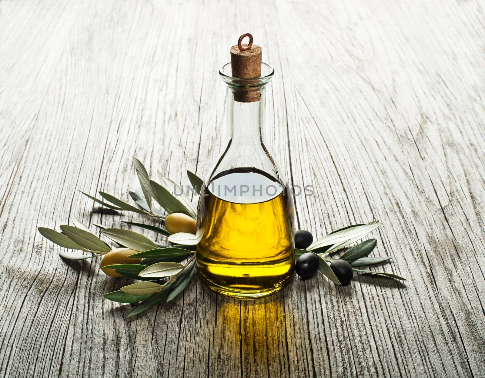 Olive oil and olive branch on a wooden background