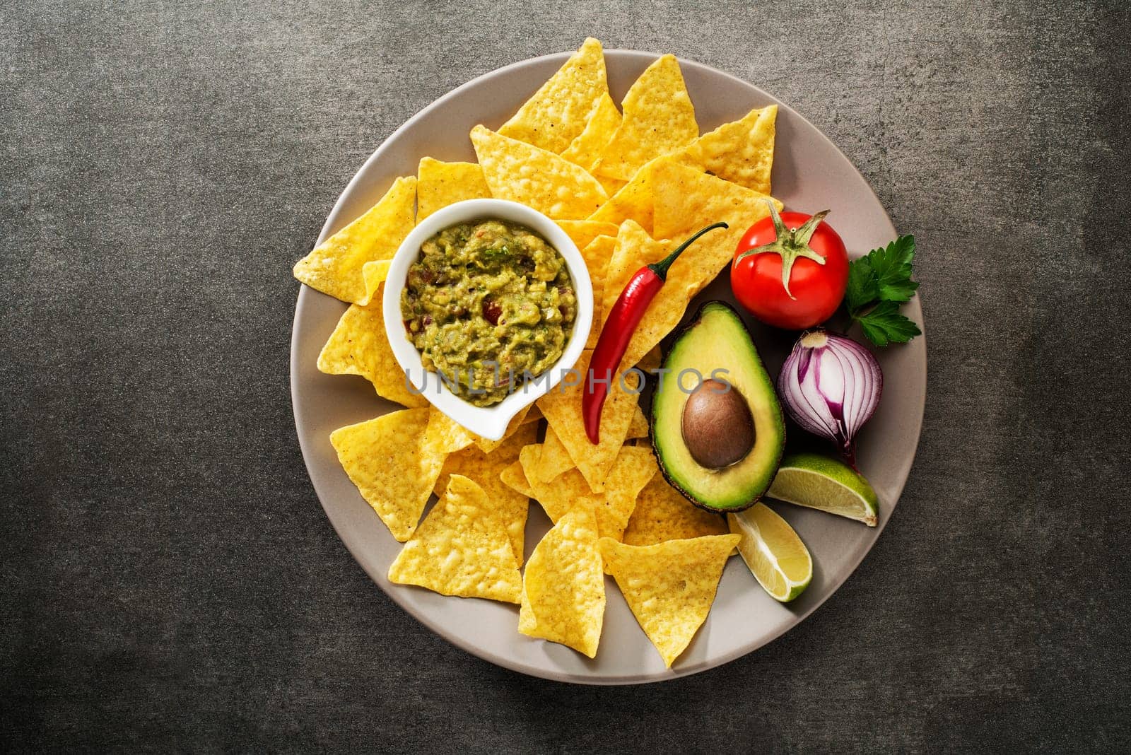 Guacamole sauce with fresh ingredients and corn nachos chips