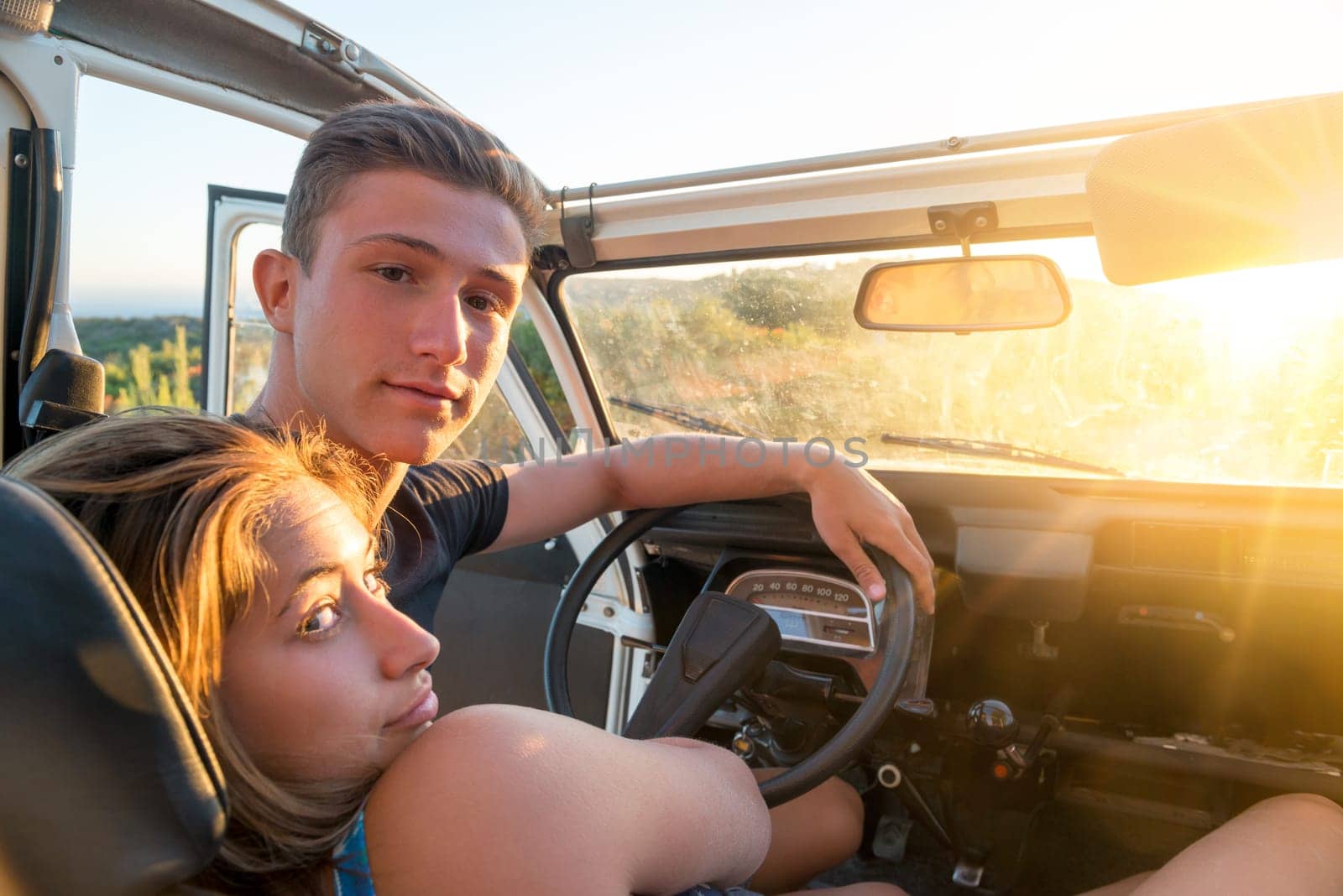 Happy couple in a car enjoying sunset.