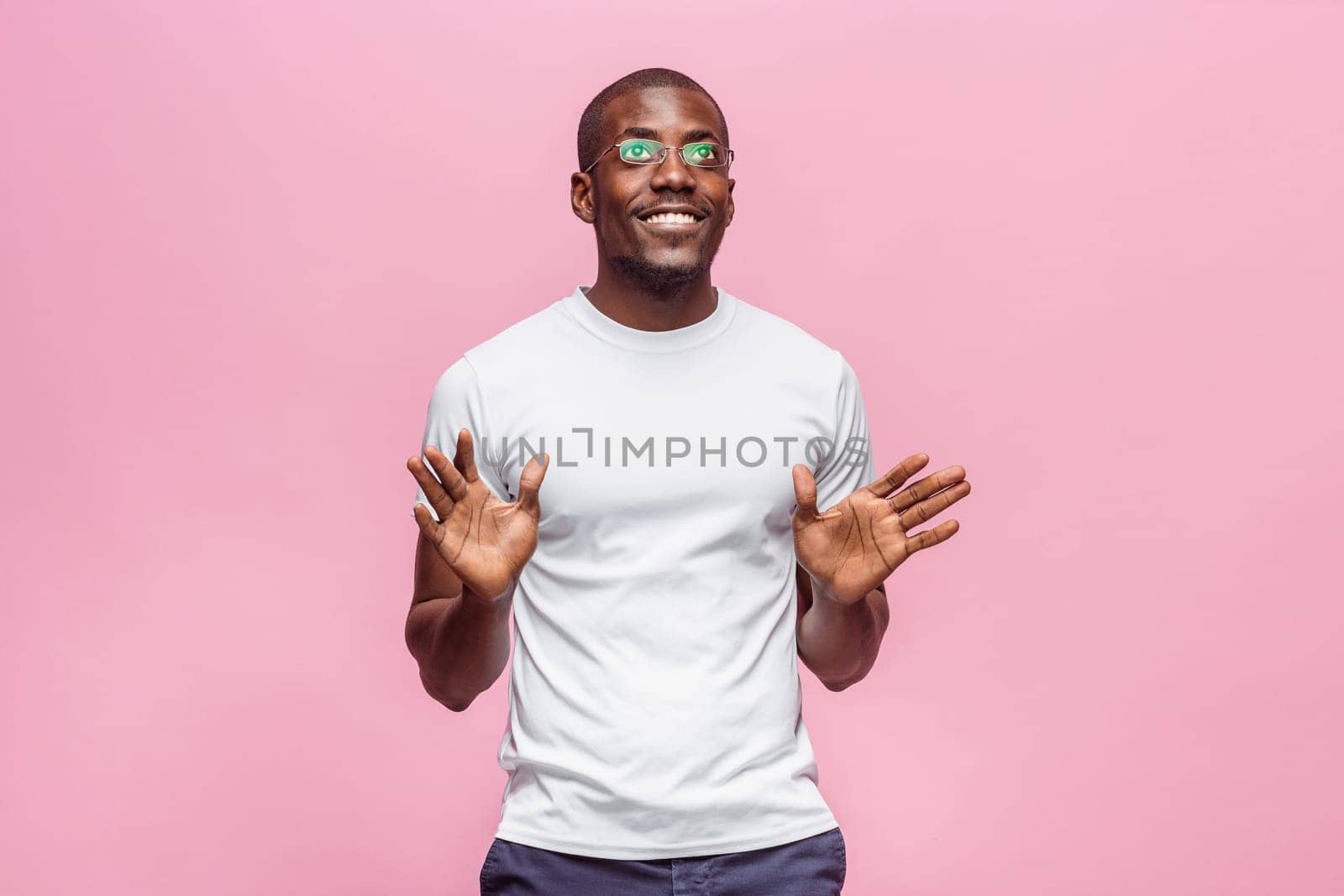 Portrait of a very happy afro american man showing emotions in studio on pink background