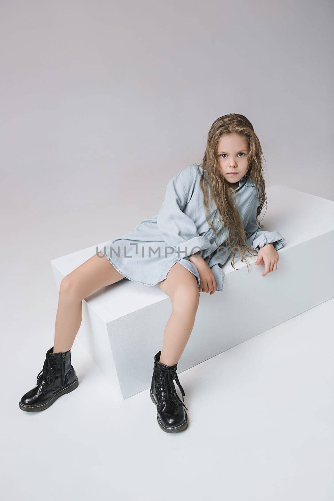 Stylish young teen girl posing at studio over gray background