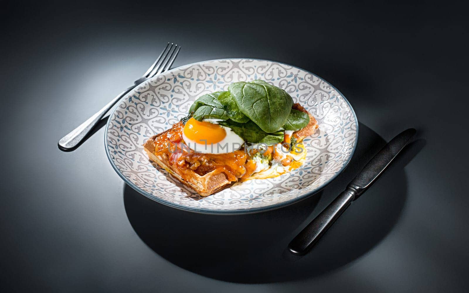 Scrambled eggs on meat with fried potatoes and toast at plate on wooden table