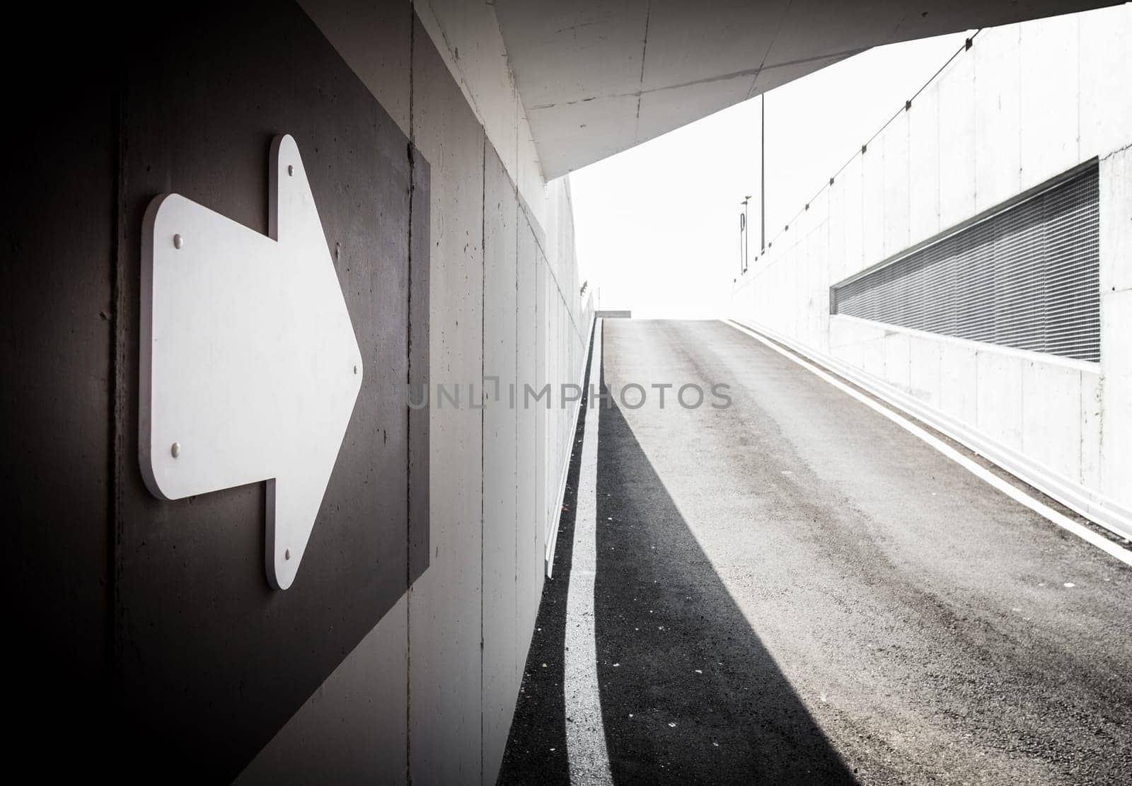 Underground parking garage exit with arrow signal. Space for text.