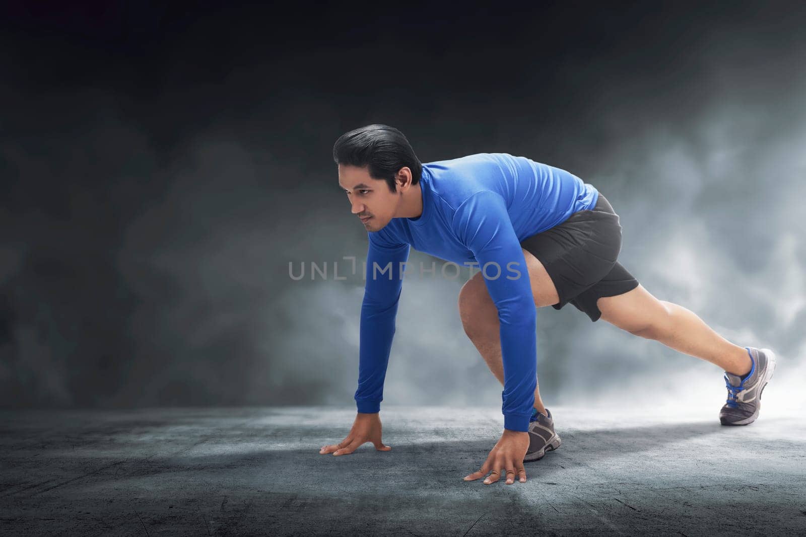 Muscular asian man ready for run with concrete floor background