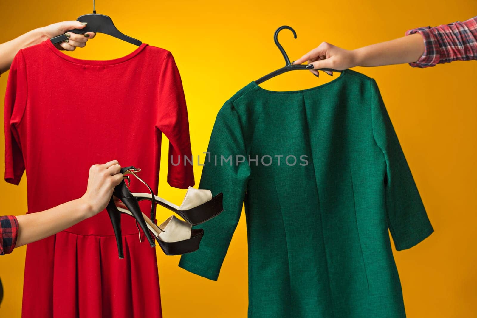 Textile, design, clothing, fashion concept. The female hands with dresses in her hands on yellow