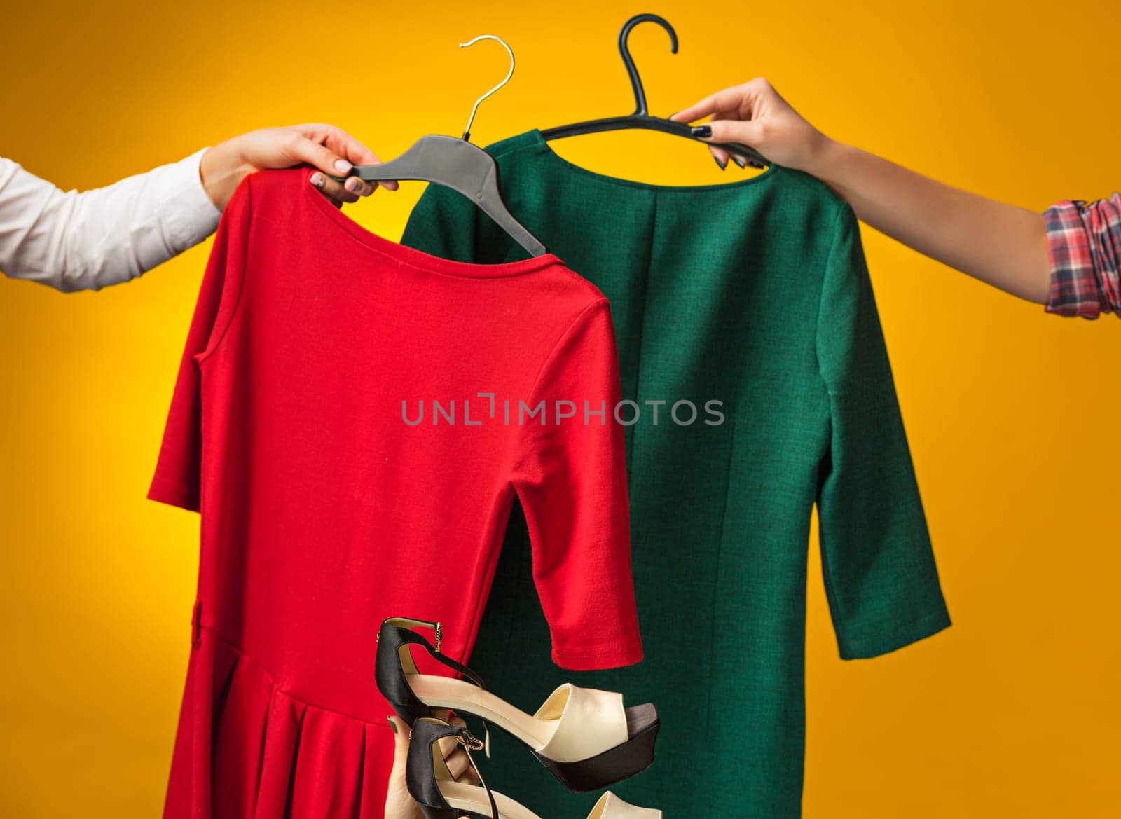 Textile, design, clothing, fashion concept. The female hands with dresses in her hands on yellow