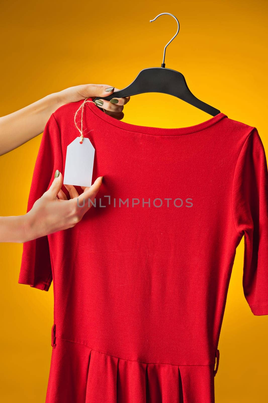 Textile, design, clothing, fashion concept. The female hands with dresses in her hands on yellow
