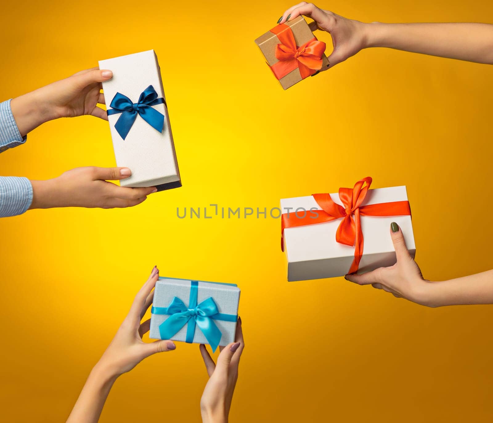 The closeup picture of man and woman's hands with gift box on yellow background