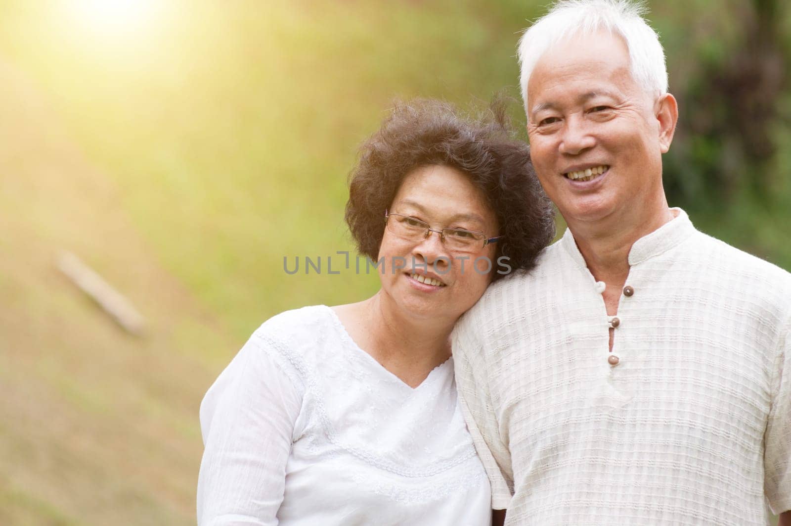 Happy Asian mature couple smiling at outdoor park.