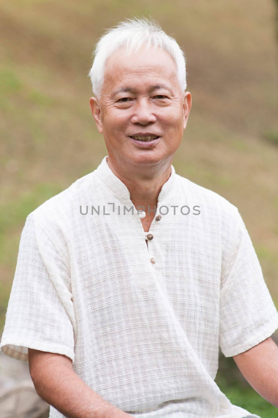 Happy Asian senior man relaxing at outdoor park.