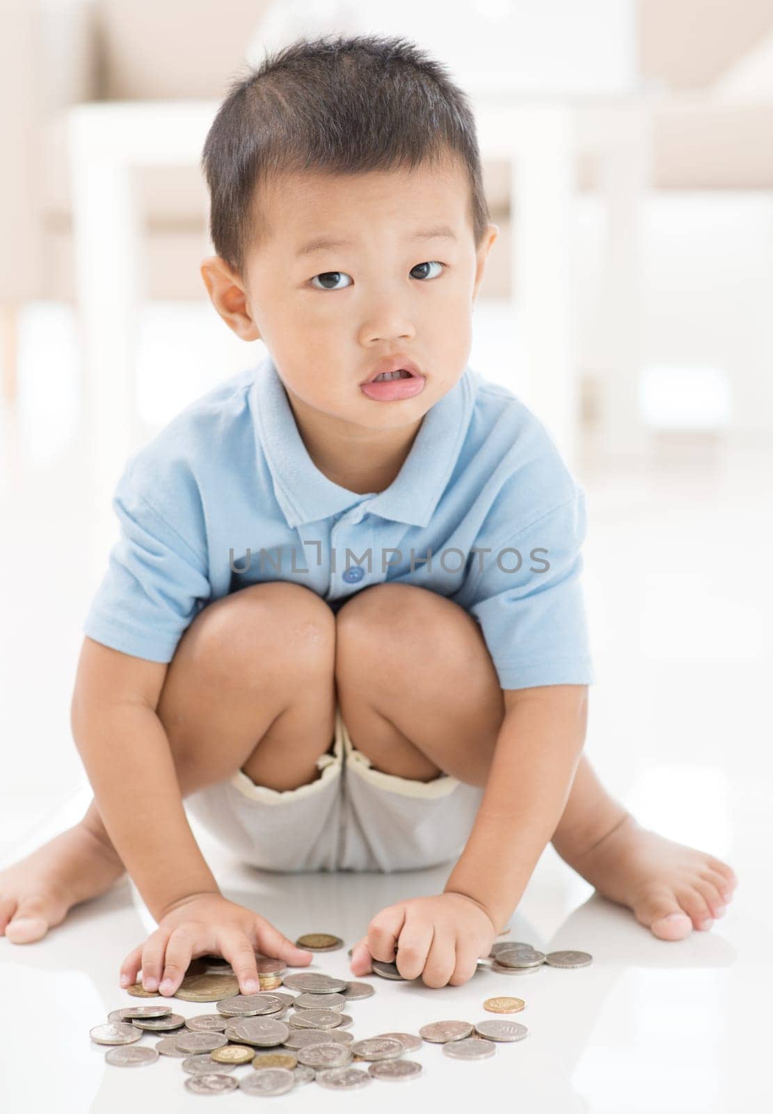 Asian preschool boy saving coins at home. Child education fund concept.