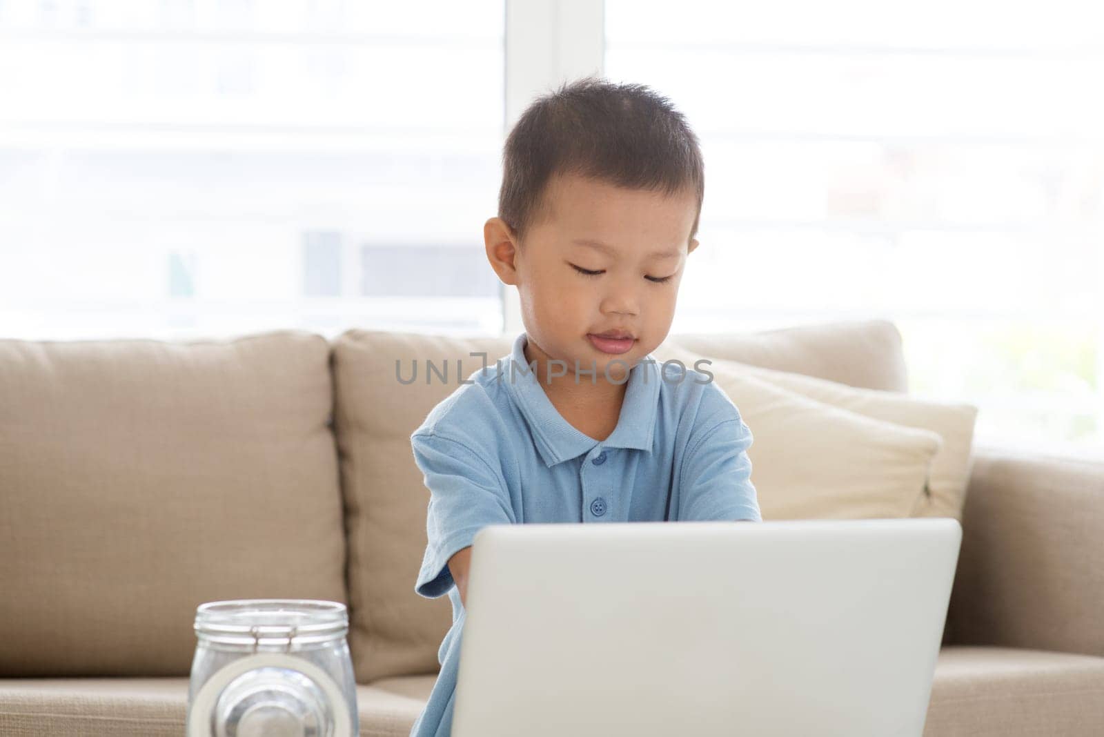 Asian boy using computer laptop at home. Child education and technology concept.