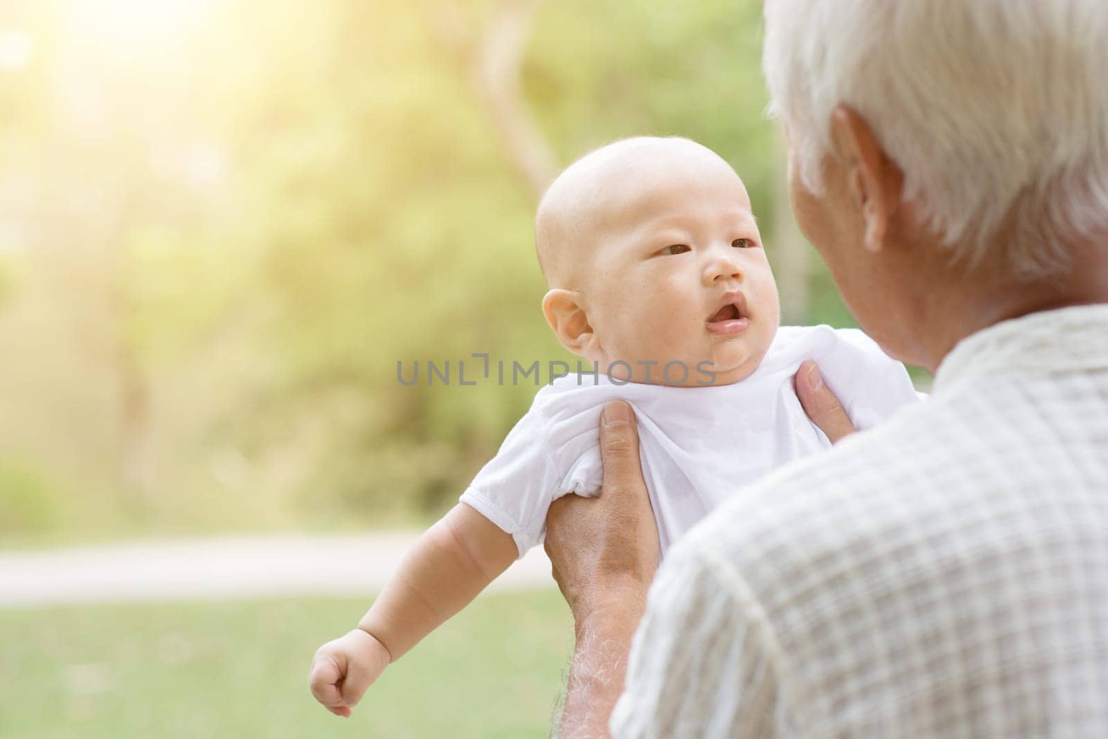 Happy grandfather with baby grandson at outdoors park. Asian family, life insurance concept.