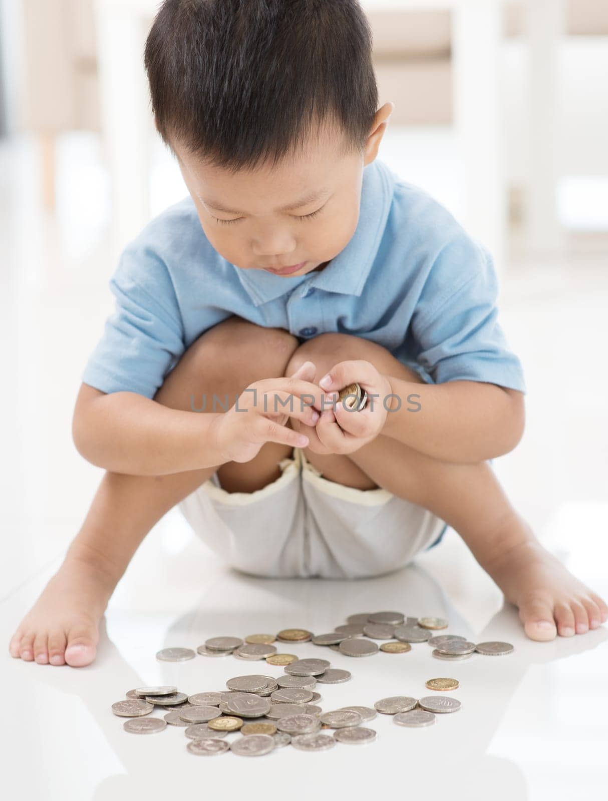 Asian boy saving coins at home. Child education fund concept.