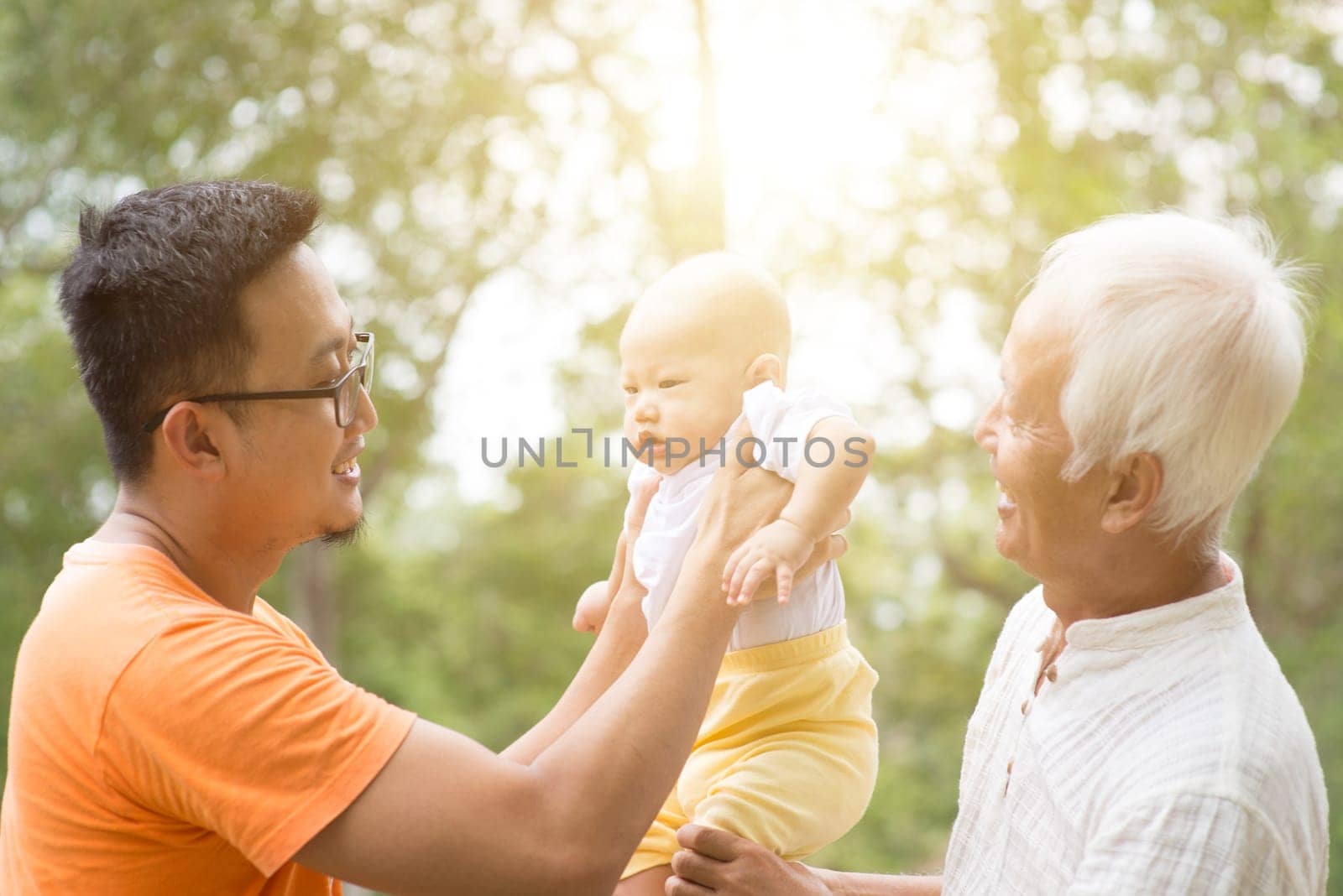 Happy grandfather, father and baby grandchild at outdoors park. Asian multi generations family.
