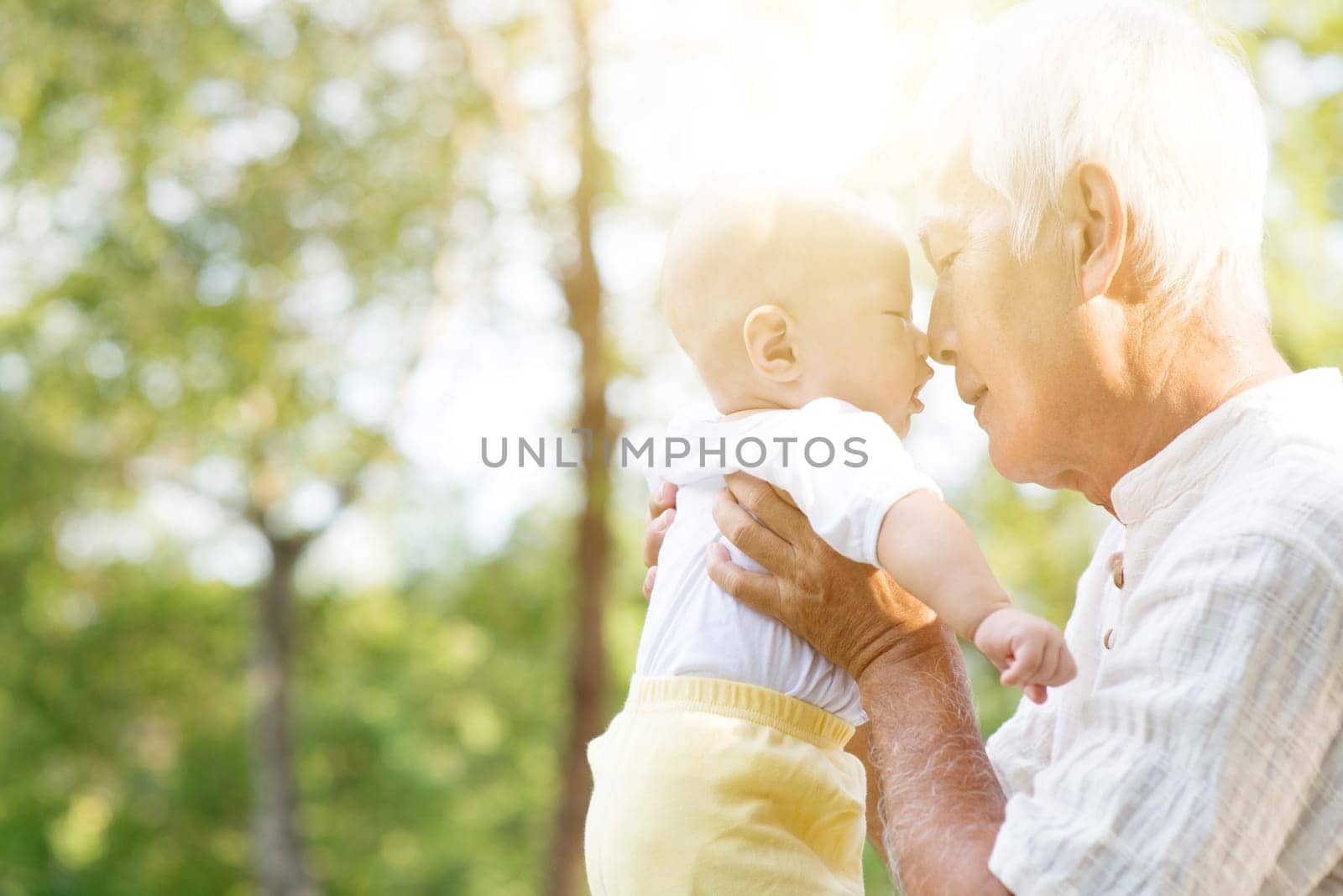Portrait of happy grandfather with grandson embracing outdoor.