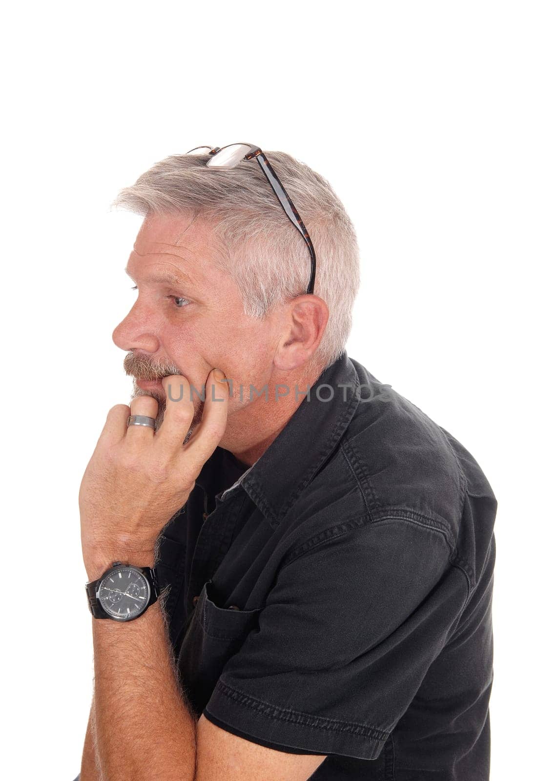 A gray hared middle aged man sitting isolated for white background with.his hand on chin and glasses on his head, isolated for white background.