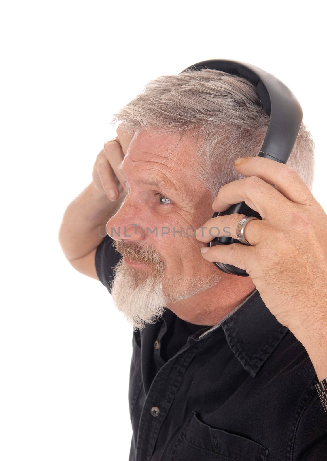 A closeup image of a middle age man with gray hair and beard putting.on his head phone listening to music, isolated for white background.
