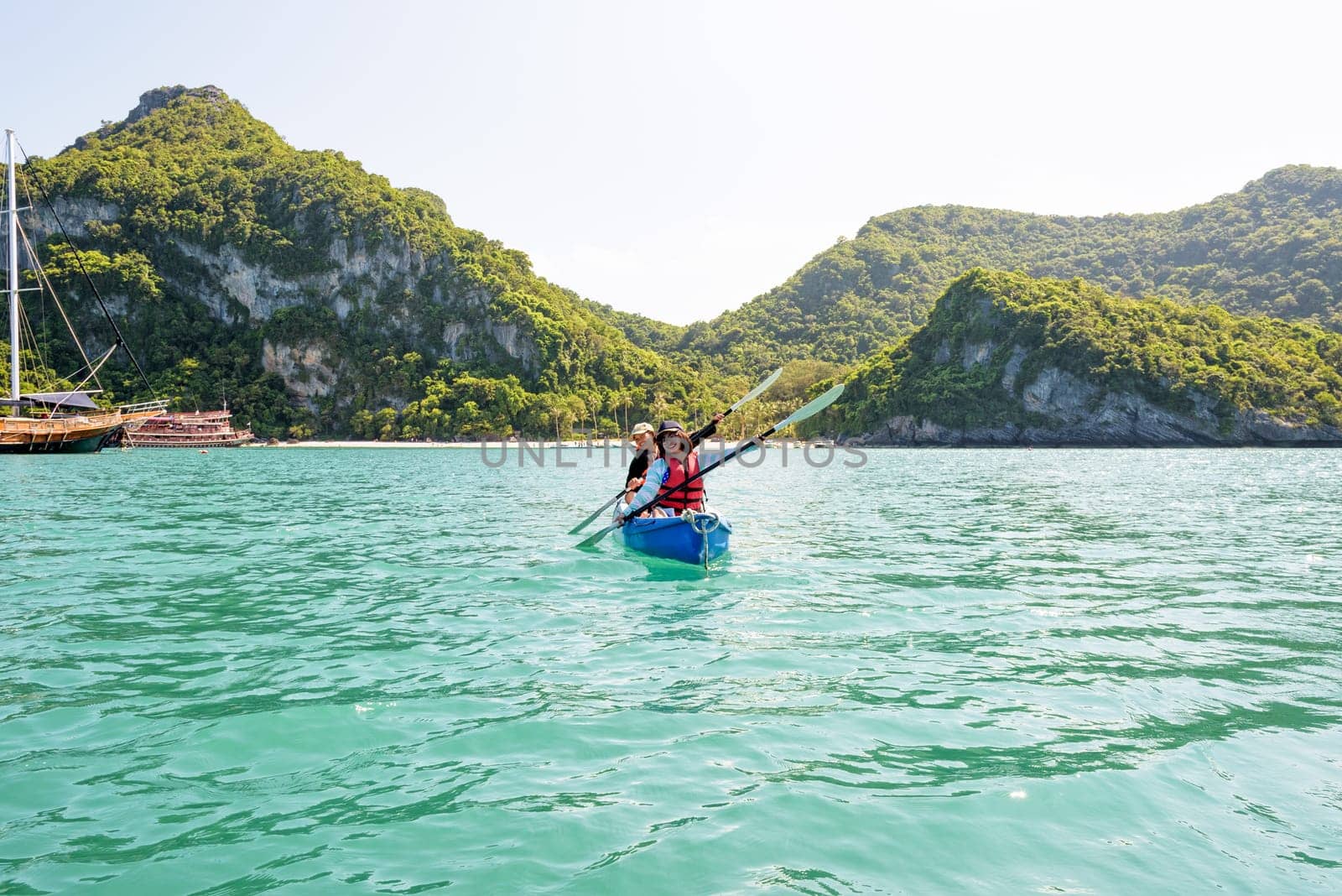 Two women are mother and daughter. Travel by boat with a kayak happy on the sea under the bright summer sky front of Ko Wua Ta lap islands at Mu Ko Ang Thong National Park, Surat Thani, Thailand