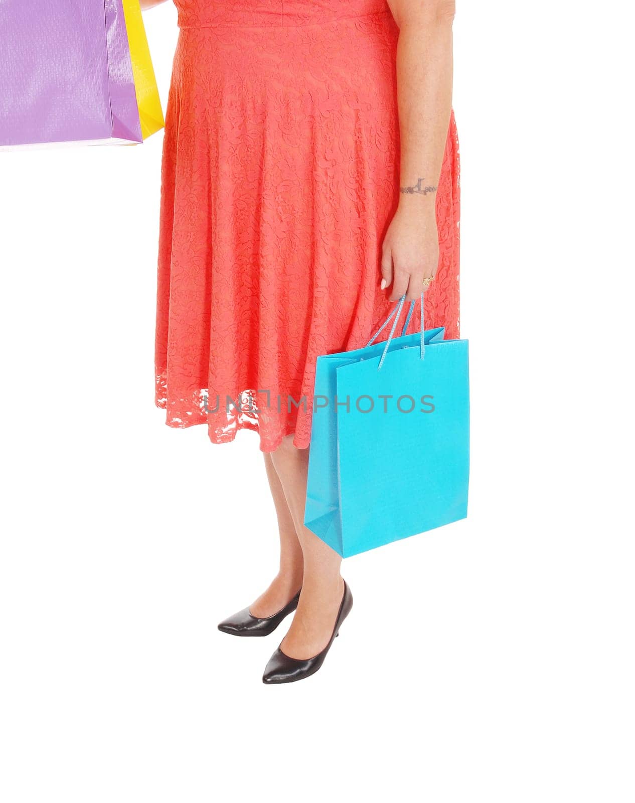 A woman standing from the waist down in a red dress holding her.shopping bags, in heels, isolated for white background.