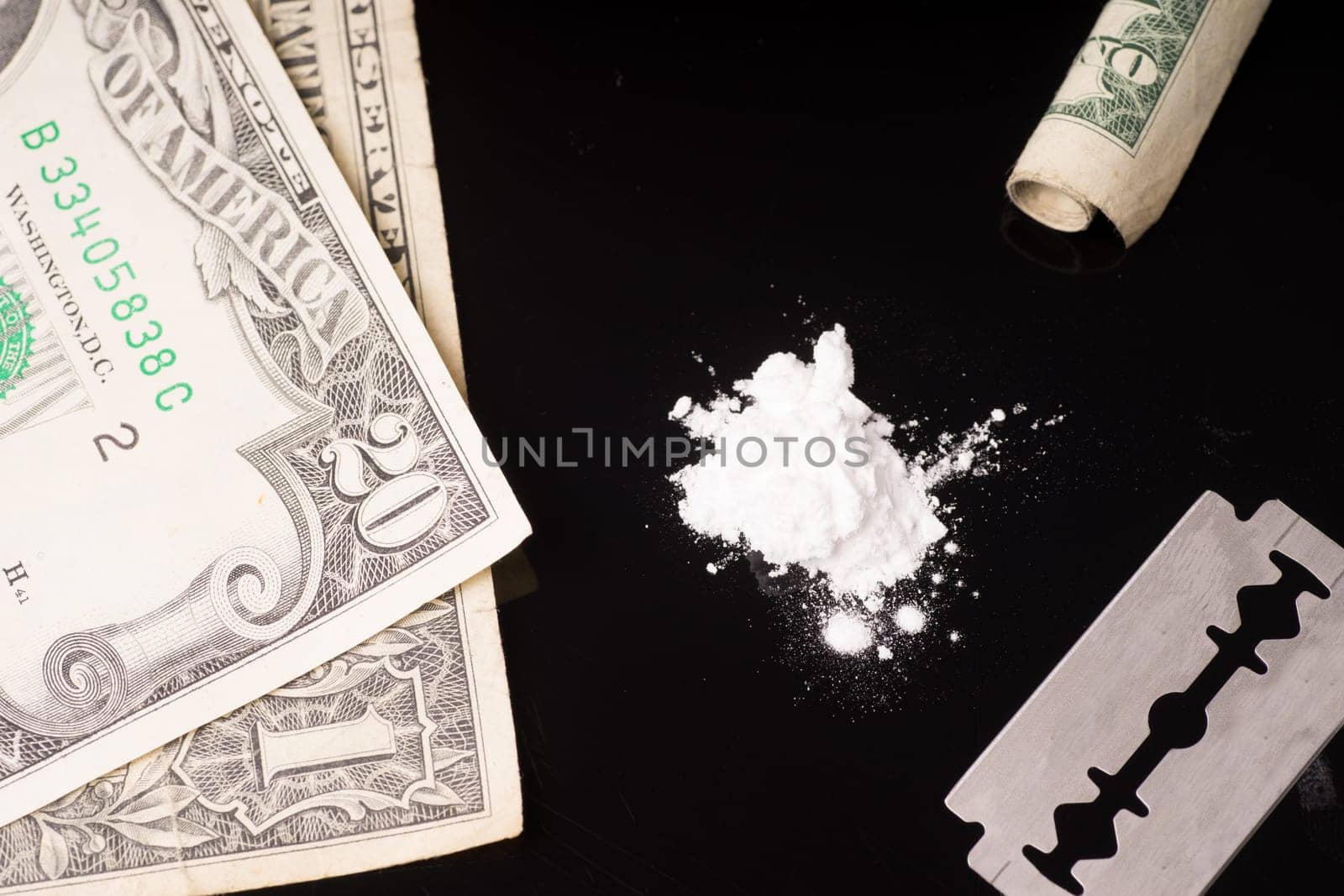cocaine or other illegal drugs that are sniffed by means of a tube, isolated on black glossy background