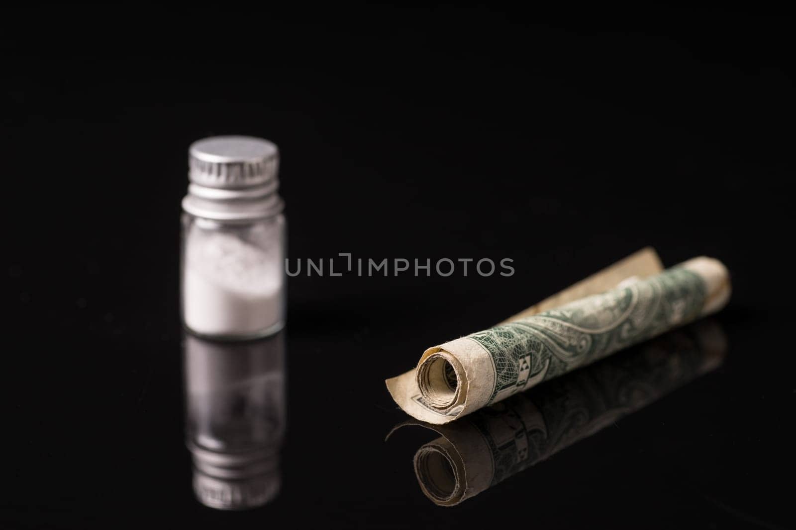 cocaine or other illegal drugs that are sniffed by means of a tube, isolated on black glossy background