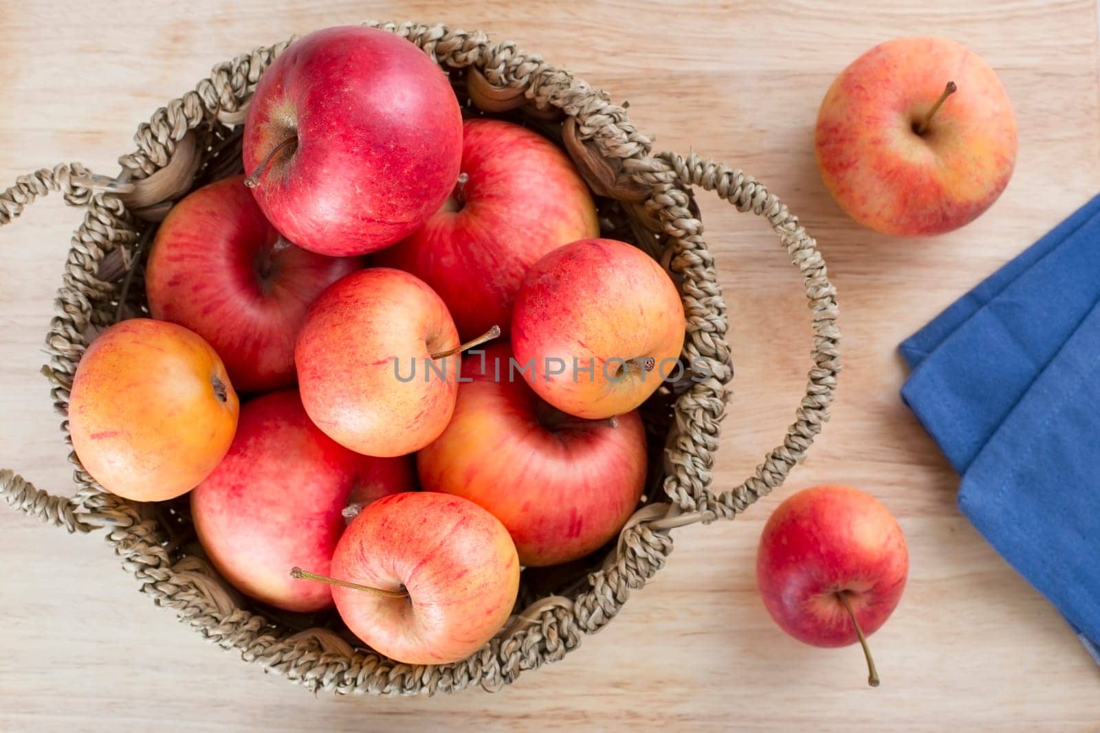 Fresh apples in a basket on a table from directly above.
