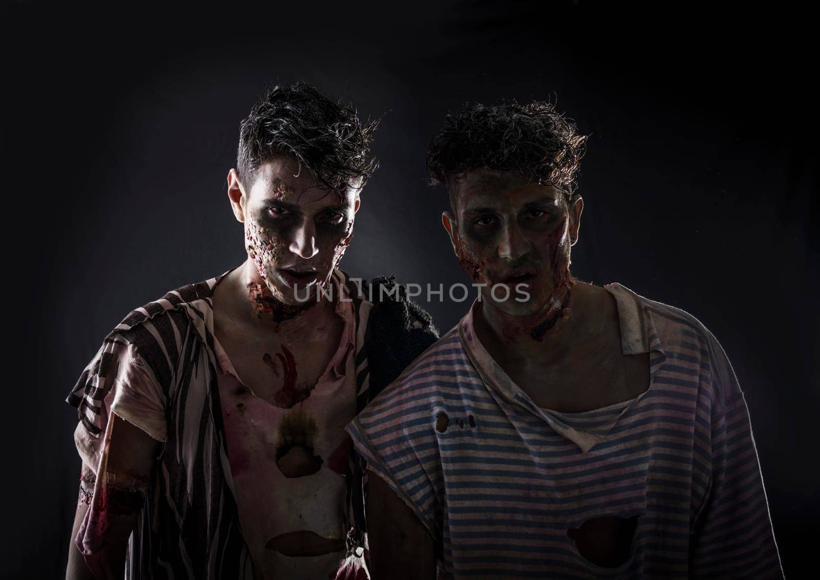 Two male zombies standing on black smoky background, head and shoulder shot. Halloween theme