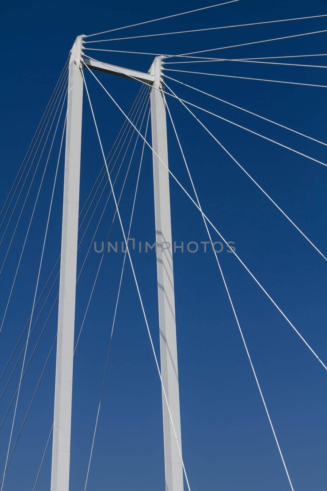 upper part of a suspension bridge with ropes and support before blue sky