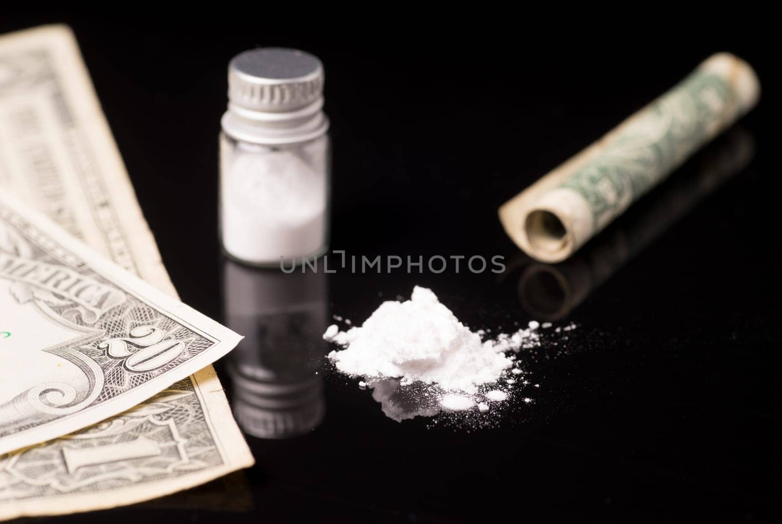 cocaine or other illegal drugs that are sniffed by means of a tube, isolated on black glossy background