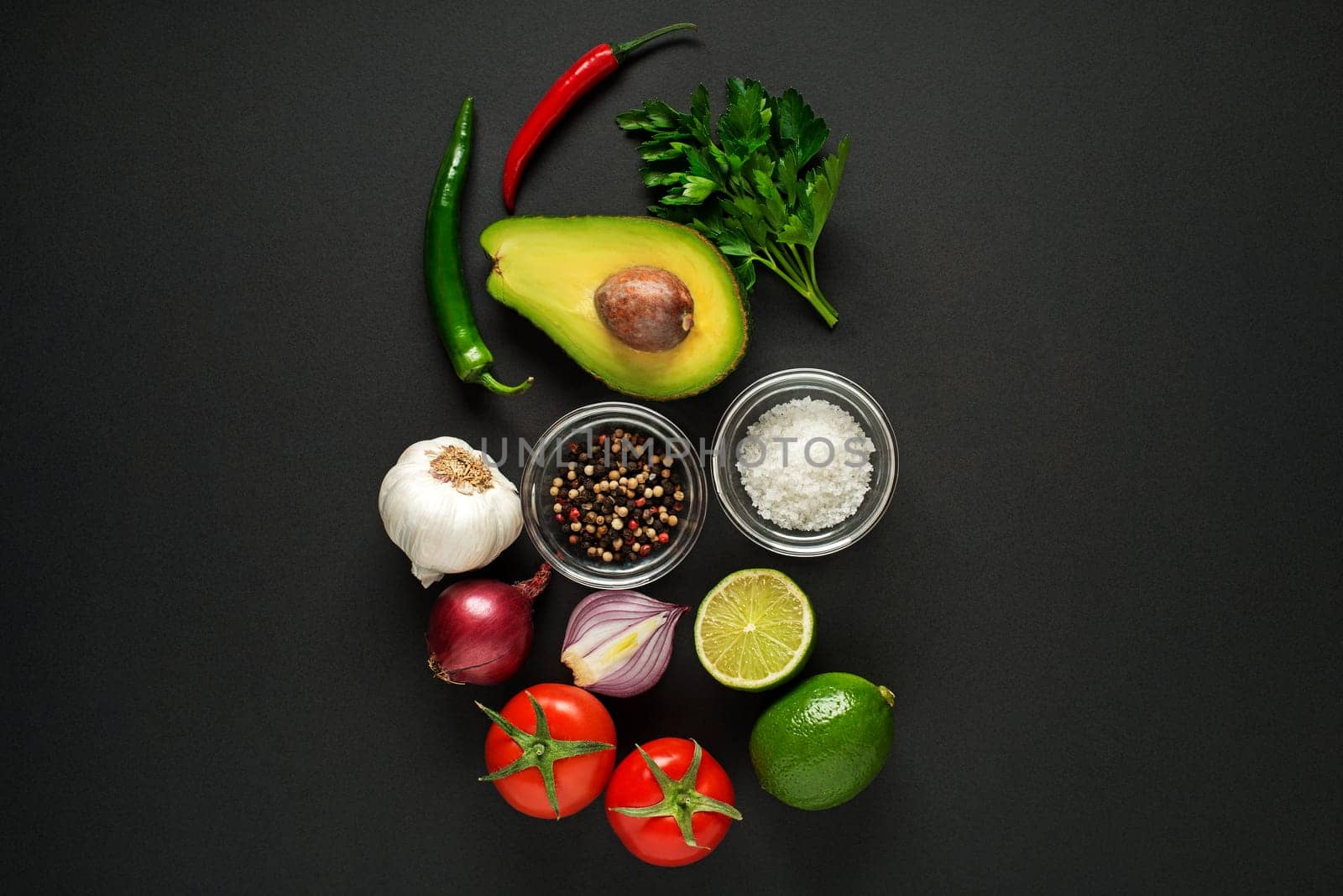 Fresh ingredients with avocado for guacamole sauce on black background