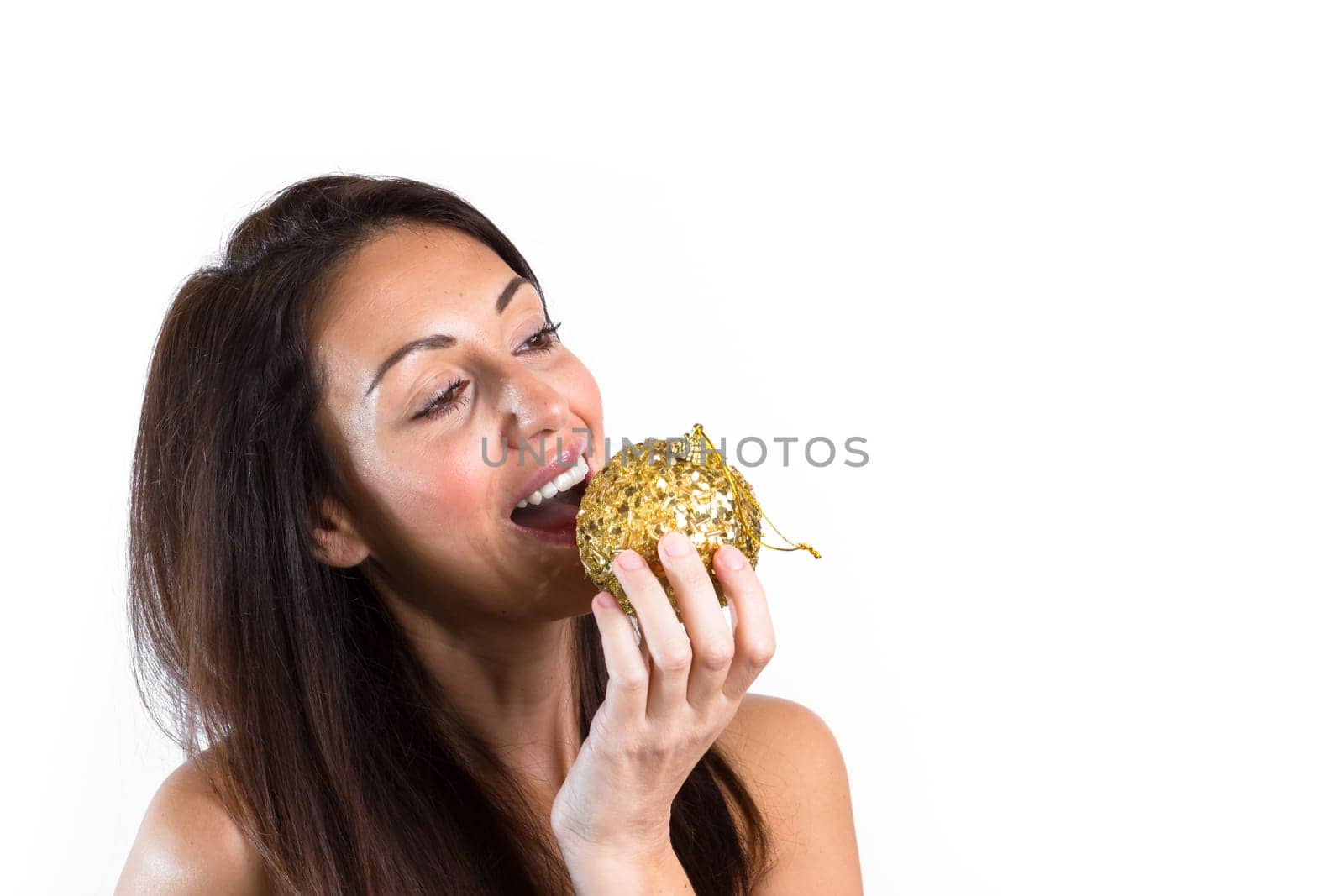 Portrait of beautiful girl want to eat a christmas ball. The young woman smiles. Ideal for Christmas or New Year holidays.