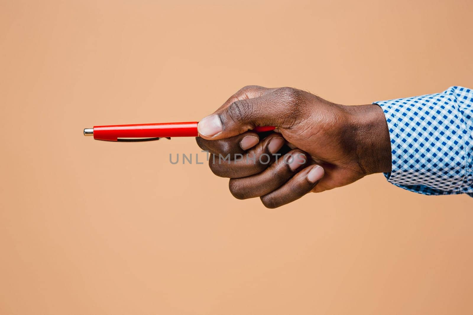 Male hand holding pencil, isolated on studio brown background