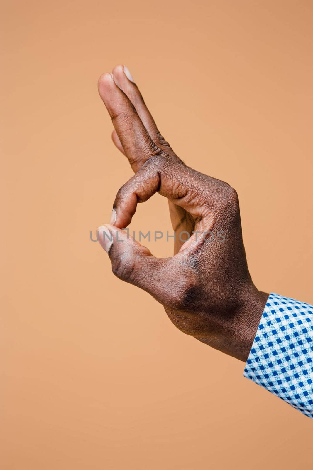 Hand showing OK sign isolated on brown background. Close-up of positive gesture, like, agreement, accept concept concept
