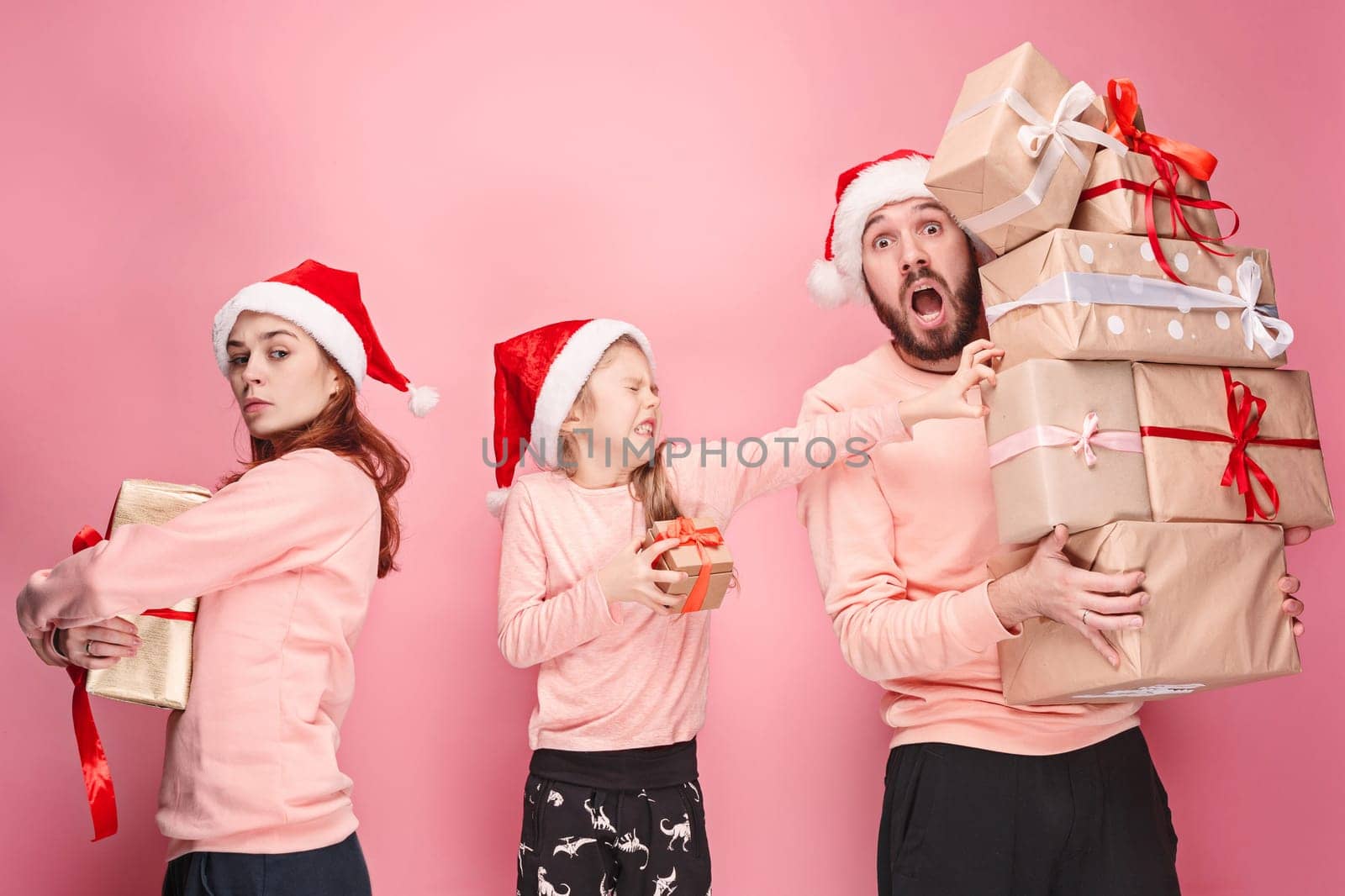 Father and mother give gifts to little daughter at pink studio background