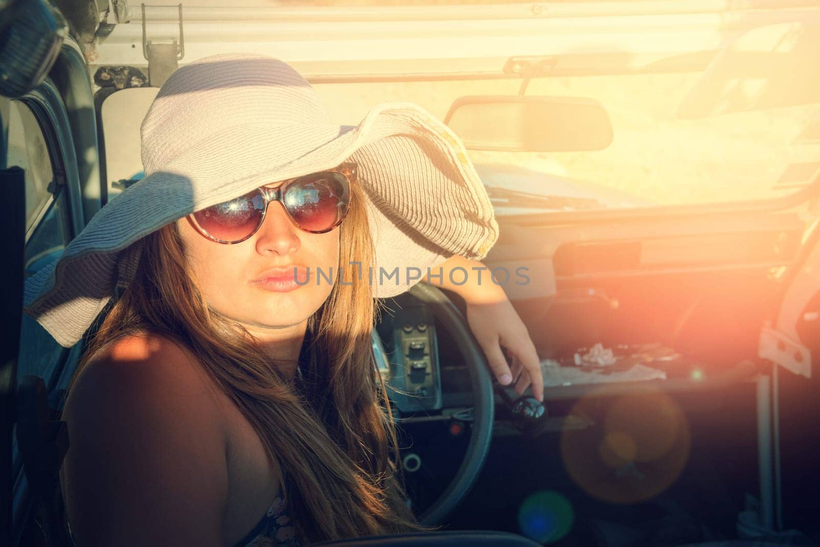 Girl posing in a car in sunset during vacations