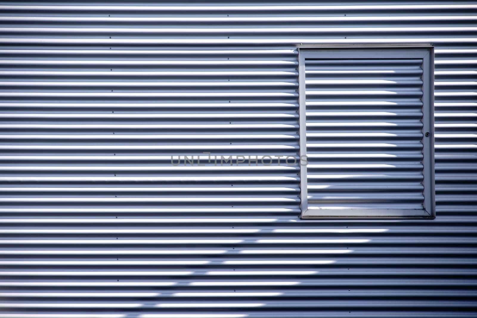 The detail of a modern façade made of corrugated sheet metal with a window frame.