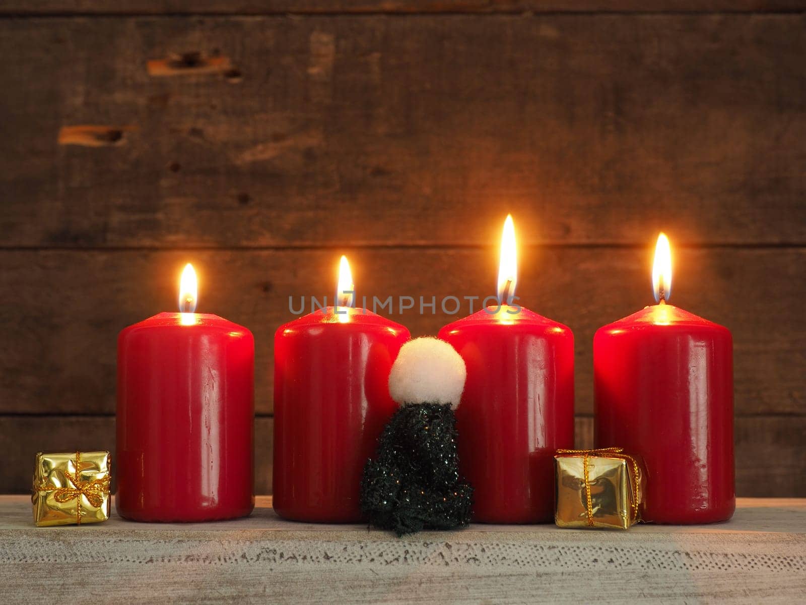 Four red Advent candles on a rustic wooden background, all candles burning, fourth Advent, Christmas concept background