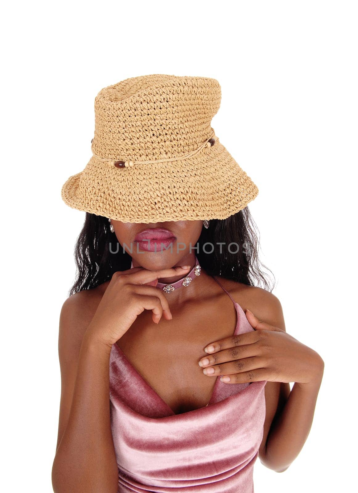 An African woman portrait standing with a straw hat over her eyes and.finger under her chin whit big lips, isolated for white background.