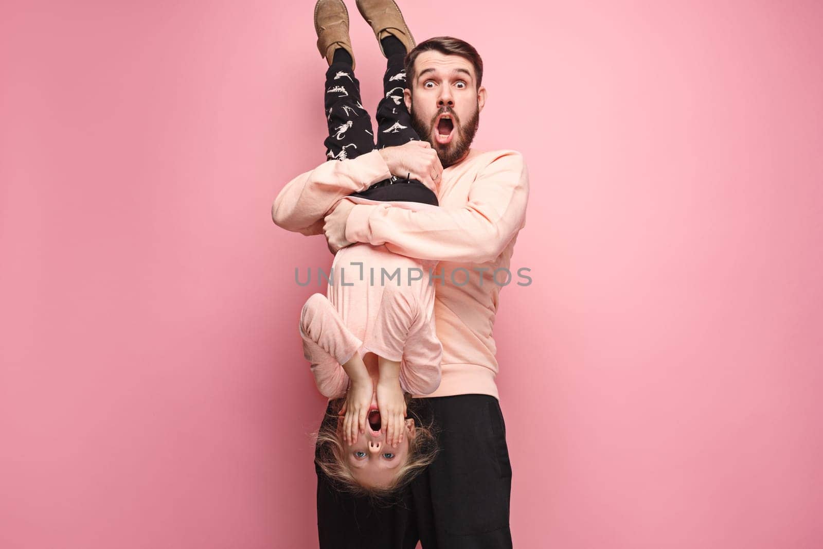 The surprised and cheerful father playing with daughter at pink studio