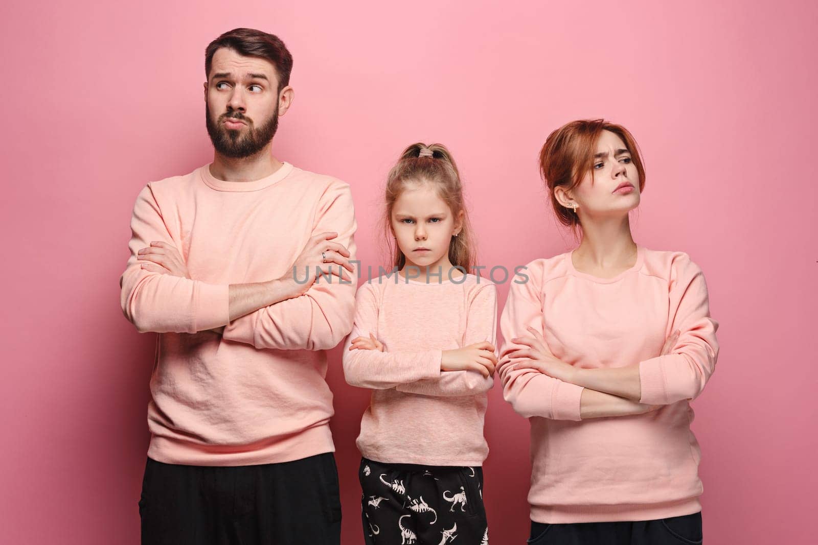 The sad and serious young family on pink studio background
